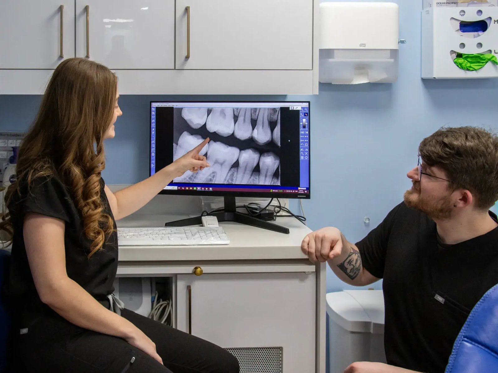 A dentist points out details on a patient’s dental X-ray